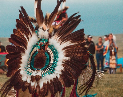 Native American Head dress with dark brown and white feathers adorned with teal beading