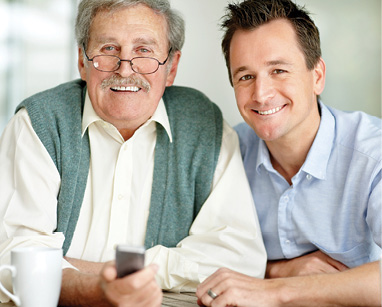 senior man and middle age son sitting together smiling for photo