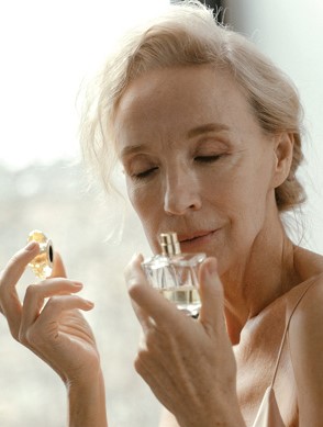 mature woman smelling her bottle of perfume