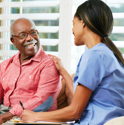 African American senior man visiting with a female clinical professional