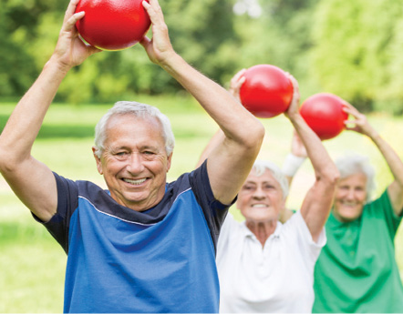 senior folks in park exercising with red weight balls