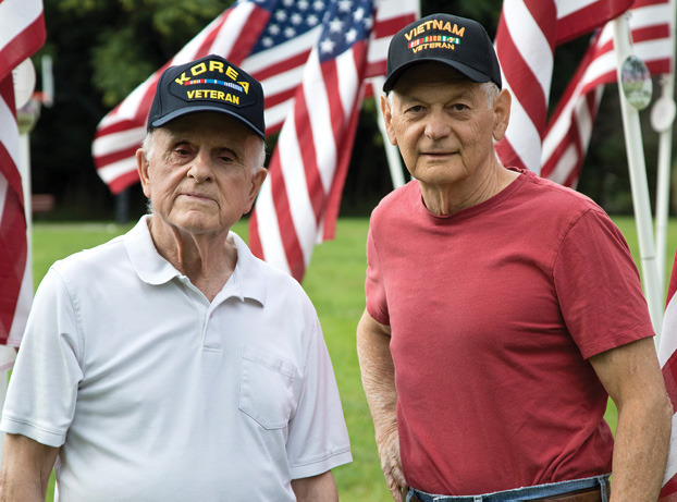 stock image of two male veterans outside with American flags waving in the background.