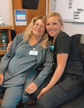 Twin Rivers Nursing and Rehab Featured Resident, Thelma, pictured with another staff member, sitting in the office