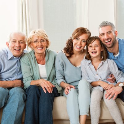 Intergenerational family, grandparents, adult son and daughter, and young granddaughter, sitting on sofa together taking a photo