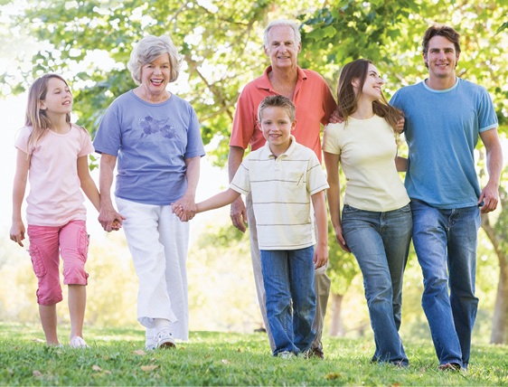 extended family walking through the park on a sunny day under the trees